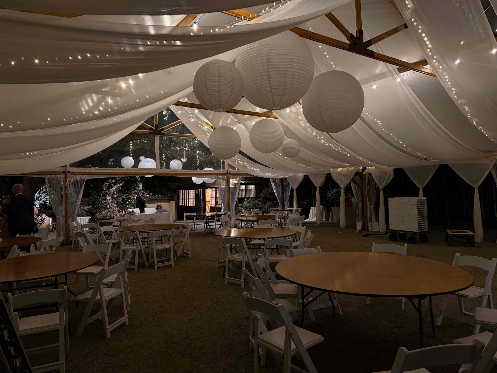 White fabric draping with suspended paper lanterns and fairy lights for a 120-guest reception