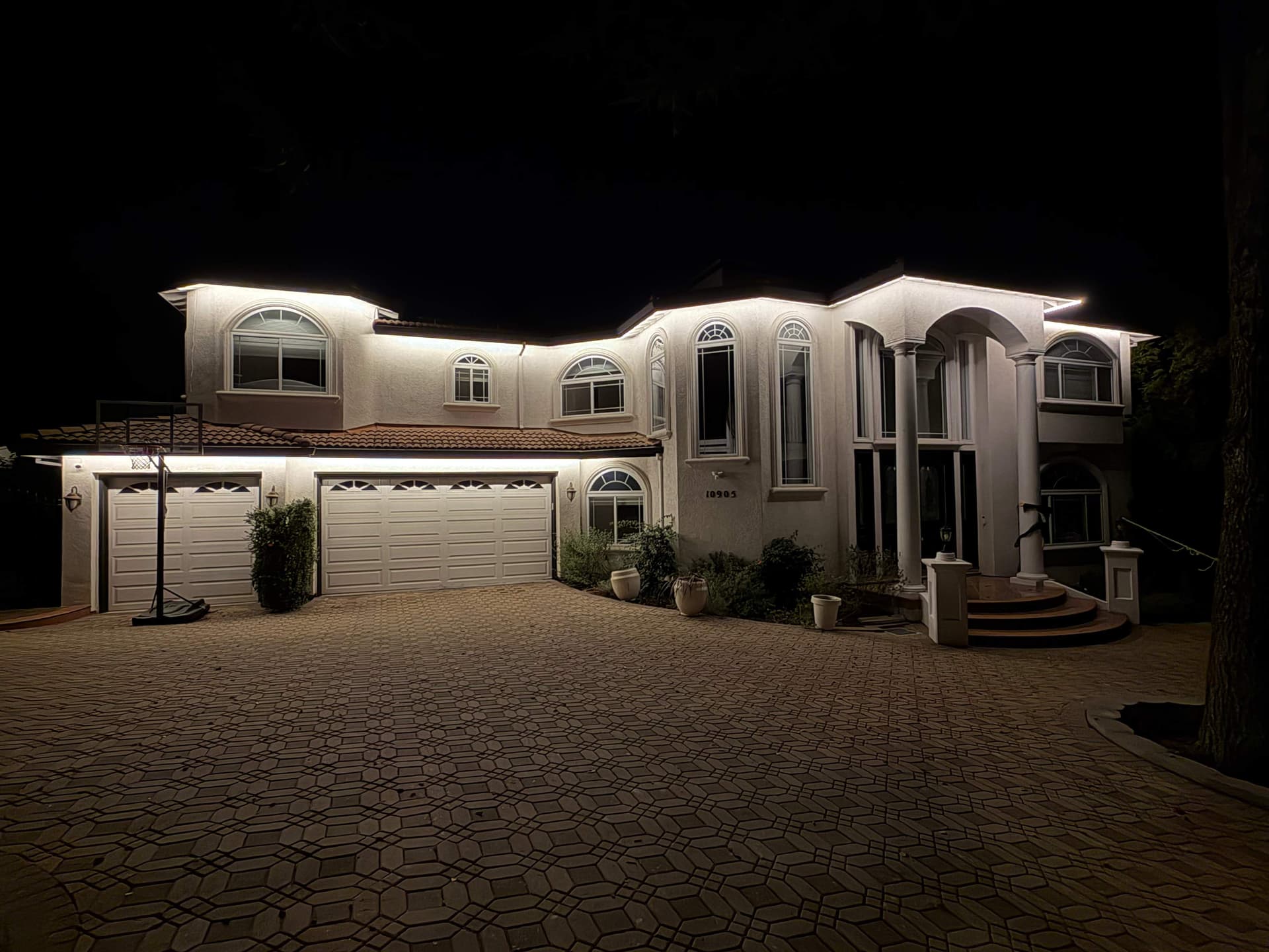 Mediterranean two-story home at night with clean warm-white Govee permanent roofline lighting installed along every eave